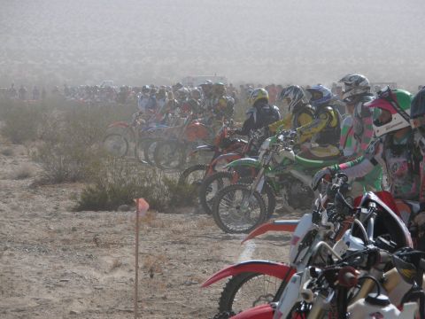 1996 Ford C-350 (Centurion Conversions) - Many dirt bikes are lined up for a race in a dusty, desert landscape.