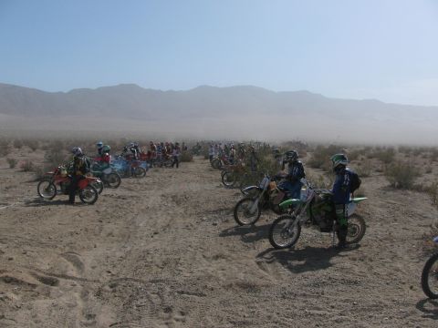 1996 Ford C-350 (Centurion Conversions) - A large group of dirt bikes and riders are gathered in a dusty desert environment.