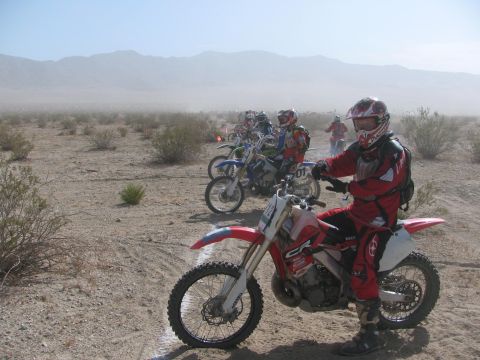 1996 Ford C-350 (Centurion Conversions) - Motorcyclists prepare for a desert race, with multiple bikes and riders visible in the dusty landscape.