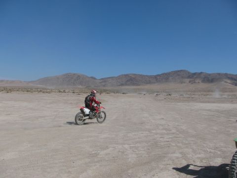 1996 Ford C-350 (Centurion Conversions) - Rider on a dirt bike in a desert scene with mountains under a clear blue sky.