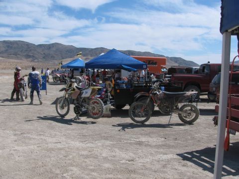 1996 Ford C-350 (Centurion Conversions) - A desert scene with multiple dirt bikes, tents, and people at an outdoor event.