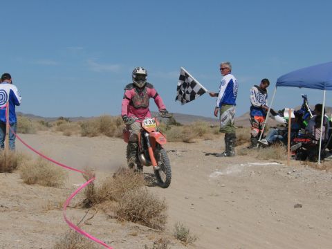 1996 Ford C-350 (Centurion Conversions) - Dirt bike race finish line with rider and official waving checkered flag.