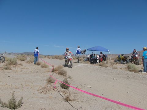 1996 Ford C-350 (Centurion Conversions) - A desert scene with a dirt bike race in progress, participants, spectators, and tents under a clear blue sky.