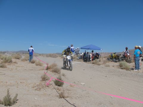1996 Ford C-350 (Centurion Conversions) - Desert race scene with multiple vehicles and participants under a clear blue sky.