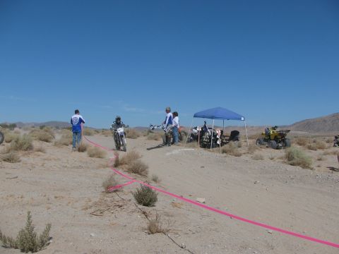 1996 Ford C-350 (Centurion Conversions) - A desert race event is underway with participants and support staff gathered under a canopy.