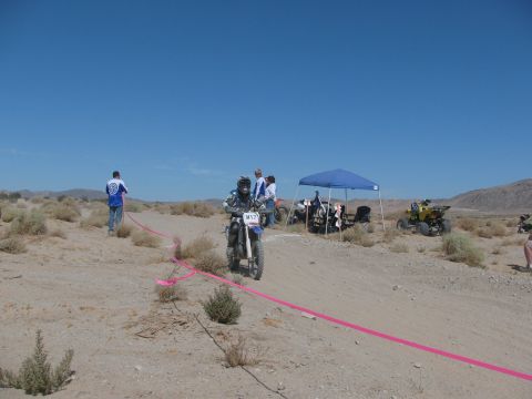 1996 Ford C-350 (Centurion Conversions) - Dirt bike race event in a desert setting with multiple vehicles and participants.