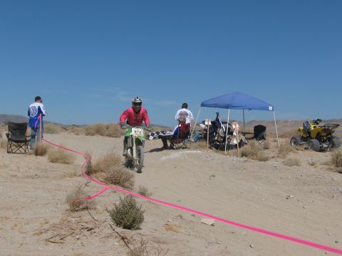 1996 Ford C-350 (Centurion Conversions) - Desert dirt bike race with rider, spectators, and an ATV under a blue canopy.