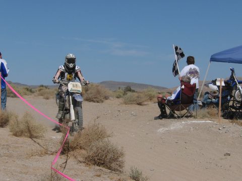 1996 Ford C-350 (Centurion Conversions) - A dirt bike race is underway with a rider approaching the finish line as spectators wave checkered flags.