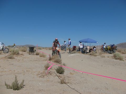 1996 Ford C-350 (Centurion Conversions) - Desert dirt bike race with participants and support vehicles under a clear blue sky.
