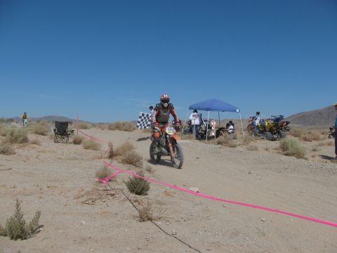 1996 Ford C-350 (Centurion Conversions) - Desert dirt bike race with multiple vehicles and spectators under a blue sky.