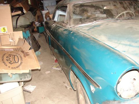 1973 Ford Ranchero - A teal-colored vehicle sits in a disorganized garage, with its front fender missing a headlight assembly.