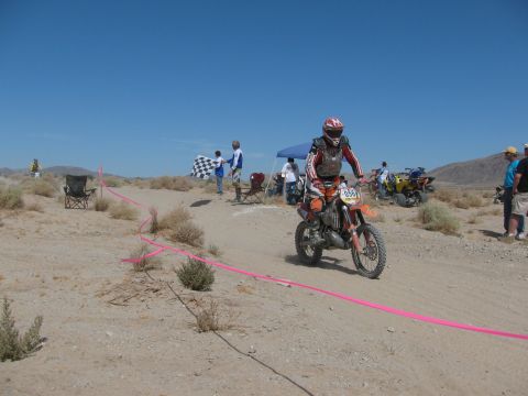 1996 Ford C-350 (Centurion Conversions) - Desert dirt bike race with rider approaching the finish line and checkered flag.