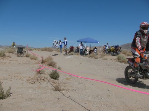 1996 Ford C-350 (Centurion Conversions) - A desert dirt bike race is underway with a checkered flag being waved and several vehicles present.