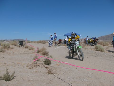 1996 Ford C-350 (Centurion Conversions) - Dirt bike race finish line with rider and officials under a blue tent.