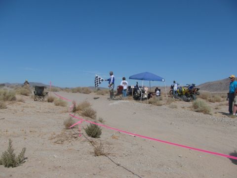 1996 Ford C-350 (Centurion Conversions) - A desert race finishes with a checkered flag waving under a clear blue sky.