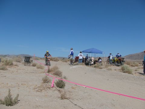 1996 Ford C-350 (Centurion Conversions) - A desert scene with dirt bike riders, spectators, and ATVs gathered under a blue canopy.
