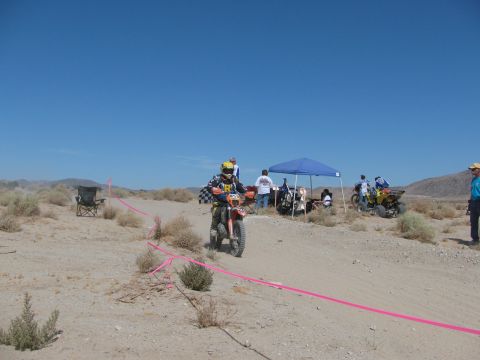 1996 Ford C-350 (Centurion Conversions) - A dirt bike race is underway in a desert landscape with spectators and support tents visible.