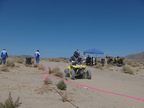1996 Ford C-350 (Centurion Conversions) - A quad bike race is underway in a desert landscape under a clear blue sky.