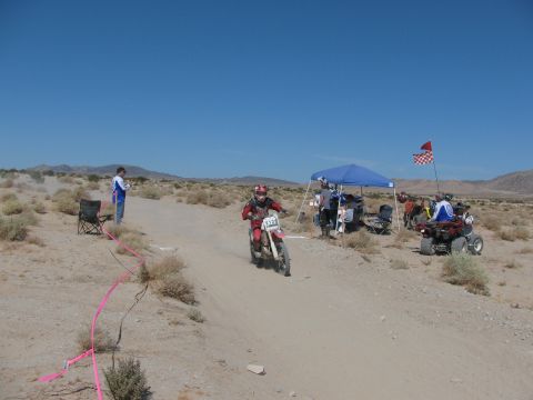 1996 Ford C-350 (Centurion Conversions) - A dirt bike race is underway in a desert landscape with spectators and support vehicles.