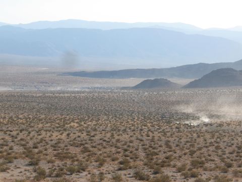 1996 Ford C-350 (Centurion Conversions) - Several vehicles are kicking up dust in a wide desert expanse under a hazy sky.