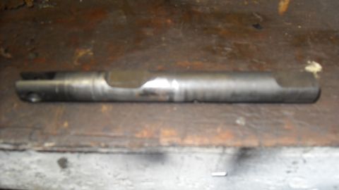 1997 Ford Ranger - A metal rod part with distinctive cutouts is shown against a wooden surface.