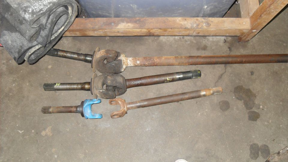Three driveshafts with U-joints, one with a blue yoke, on a concrete floor