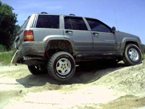 1991 Ford Bronco - This silver SUV navigates a sandy incline under a clear blue sky.