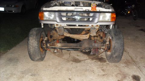 1997 Ford Ranger - The front axle and suspension of a 1997 Ford Ranger are visible, with the vehicle supported by jack stands.