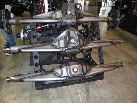 1986 Ford Bronco - Custom rear axles are displayed at an automotive show.