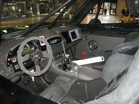 1986 Ford Bronco - The interior of a heavily modified off-road vehicle features racing seats, a Momo steering wheel, and a modern navigation system.