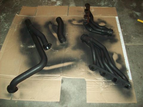 1985 Ford Bronco - Exhaust components are laid out on cardboard, appearing to be freshly painted.