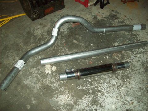 1985 Ford Bronco - Various exhaust system components laid out on a garage floor.