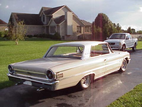 1963 Ford Galaxie - A tan 1963 Ford Galaxie coupe is parked on a driveway, with a white pickup truck in the background.