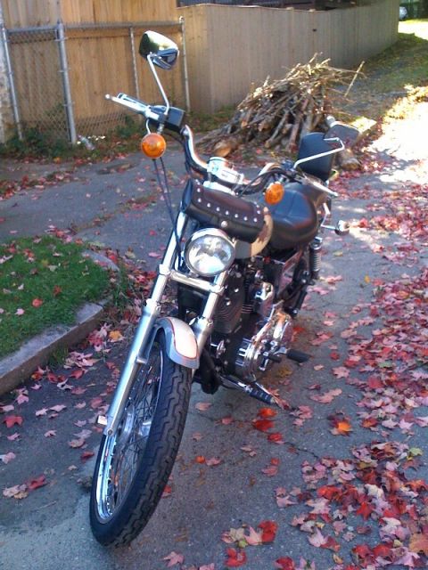 2001 Ford Crown Victoria - Motorcycle parked on street with autumn leaves scattered around.