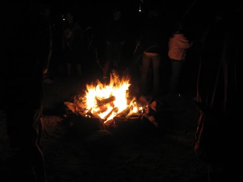 1996 Ford C-350 (Centurion Conversions) - People gather around a bright campfire at night, with sparks rising into the darkness.