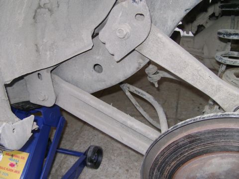 1998 Ford Crown Victoria - Close-up view of a vehicle's rear suspension system, supported by a hydraulic jack.