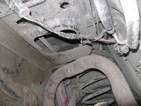 1998 Ford Crown Victoria - The underside of a vehicle reveals its exhaust system, suspension components, and exposed wiring.