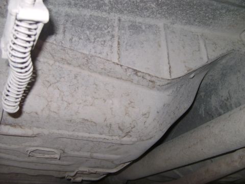 1998 Ford Crown Victoria - Close-up view of a vehicle's undercarriage, highlighting a spring and exhaust system components.