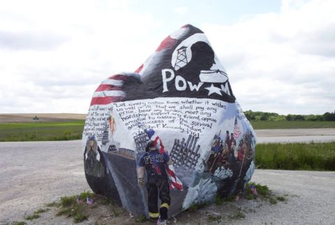 1981 Ford Bronco - A large rock is painted with various patriotic themes and quotes, set against a rural landscape.