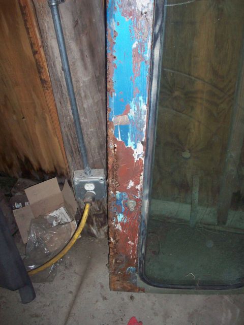 1978 Jeep CJ5 - Close-up of a heavily rusted door frame, showing layers of blue and red paint peeling away.