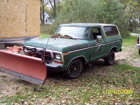 1979 Ford Bronco - A green 1978 Ford Bronco is parked outside with a snow plow mounted on its front end.