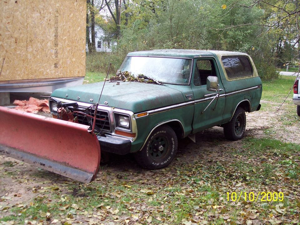 Green 1978 Ford Bronco with a red snow plow attached to the front