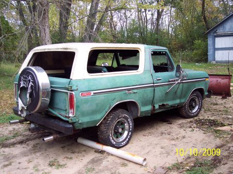 1979 Ford Bronco - A weathered 1978 Ford Bronco sits outdoors with a snow plow attachment nearby.