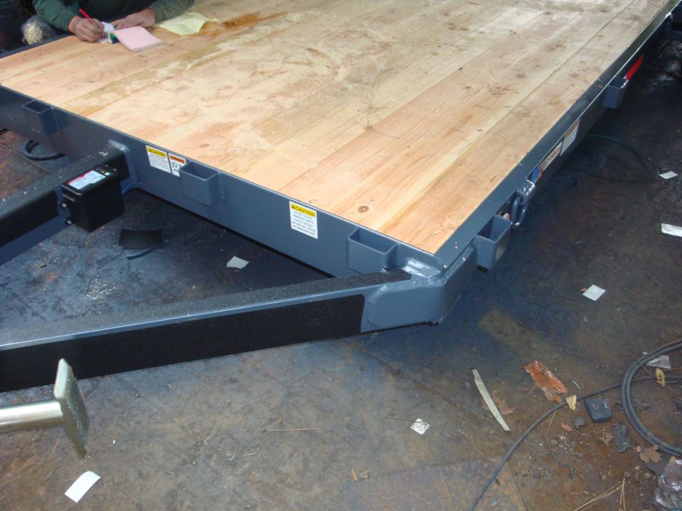 Trailer deck with wooden planks, metal frame, and a person writing on a notepad