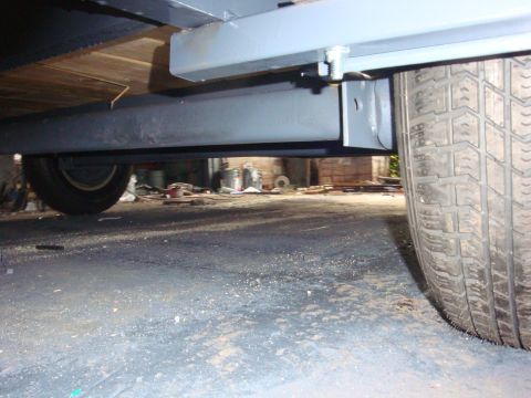 1988 Ford F-350 - Underside view of a trailer's frame and wheel assembly in a workshop setting.