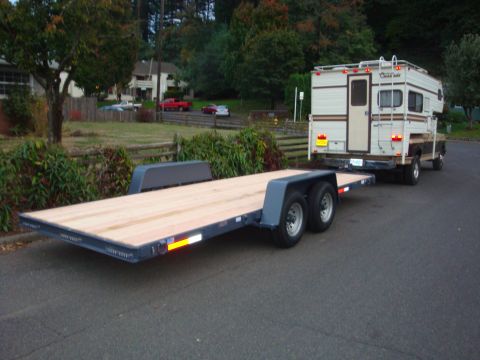 1988 Ford F-350 - A flatbed trailer is attached to a pickup truck carrying a camper shell, seen from the rear.