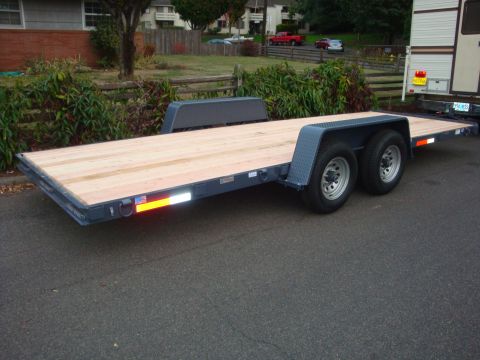 1988 Ford F-350 - A dark gray flatbed trailer with a new wooden deck and dual axles is parked on an asphalt surface.