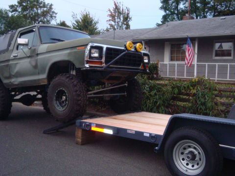 1988 Ford F-350 - A heavily modified Ford Bronco is positioned on a trailer ramp in front of a residential house.
