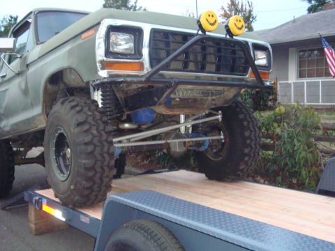 1988 Ford F-350 - Modified Ford F-Series truck with large tires and off-road bumper is loaded onto a trailer.
