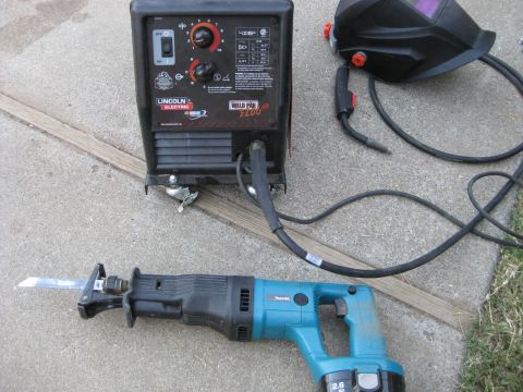 1995 Ford Bronco - A Lincoln Electric Weld Pak 100 welder, Makita reciprocating saw, and welding helmet are laid out on concrete.